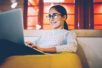 Woman With Glasses on Laptop Smiling